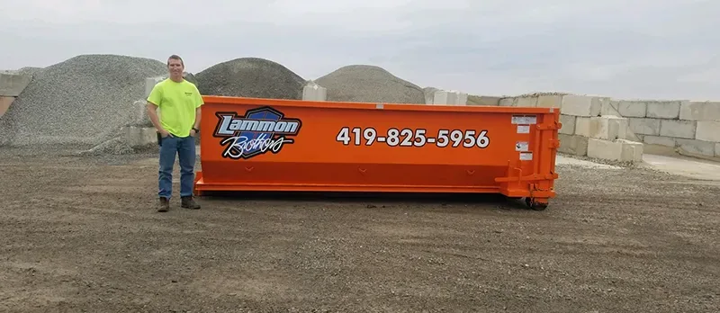 Owner standing beside a 15-yard Lammon Brothers roll-off dumpster for scale