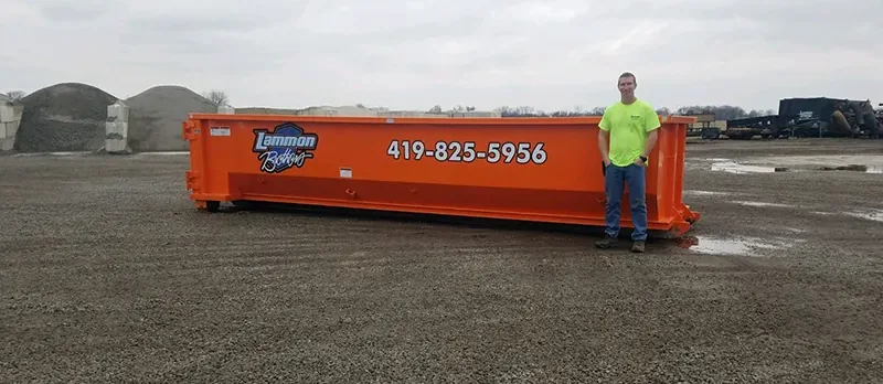 Owner standing beside a 20-yard Lammon Brothers roll-off dumpster for scale
